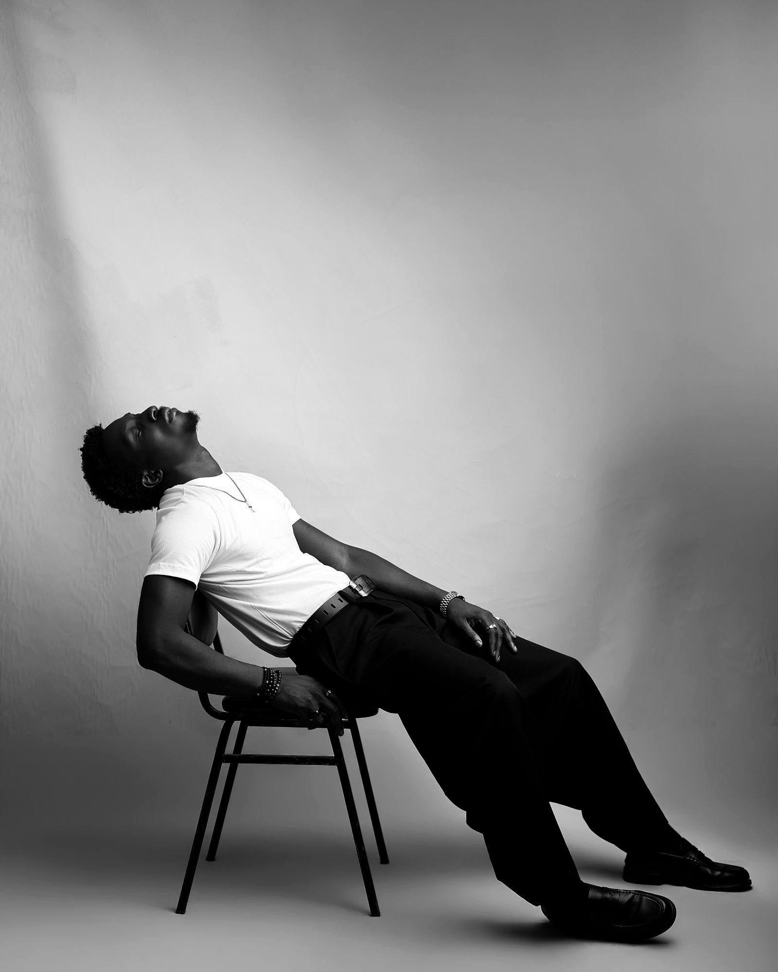 Greatman Takit reclined back over a chair, head tilted upward.