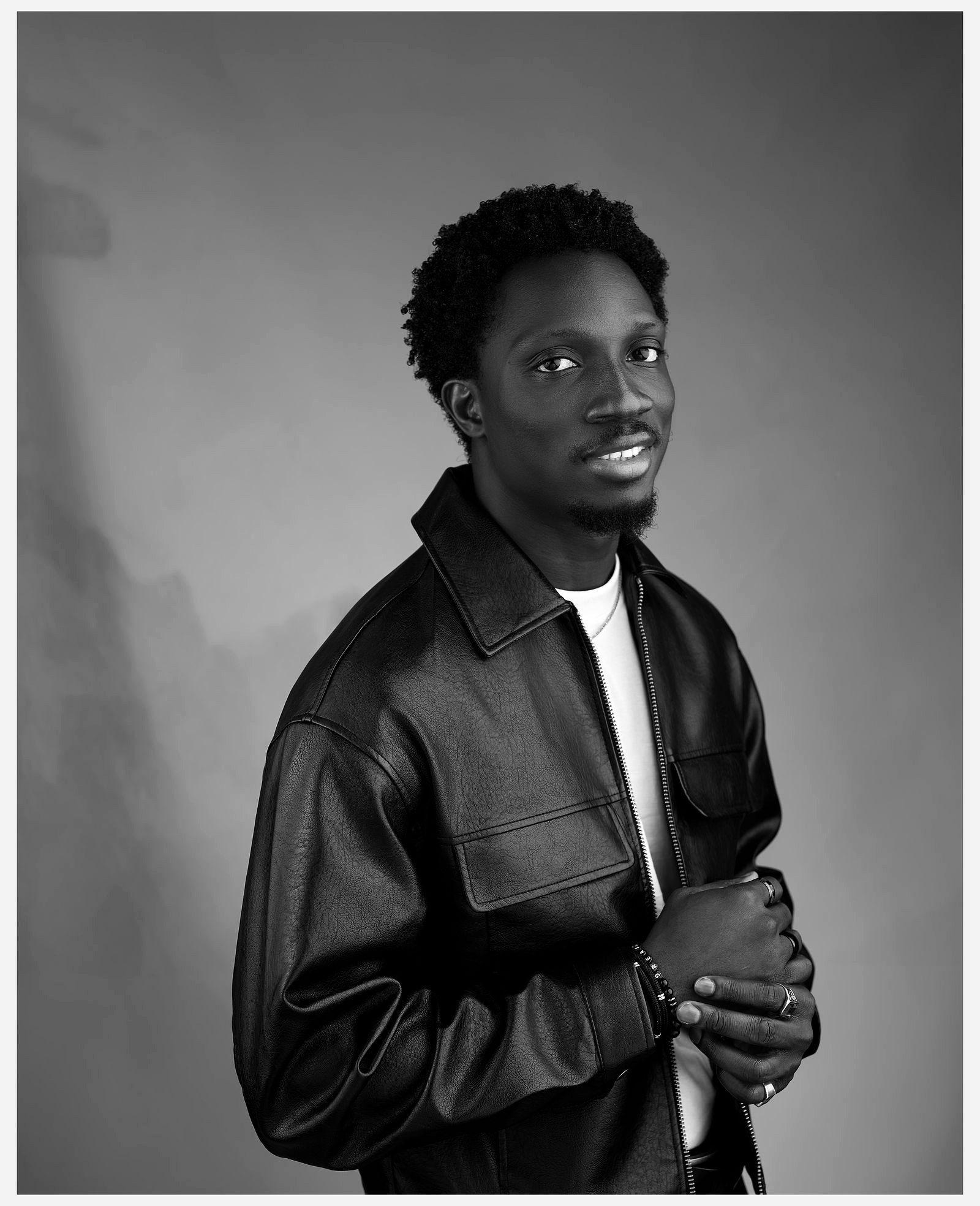 Greatman Takit in a leather jacket with his hands clasped in front of him.