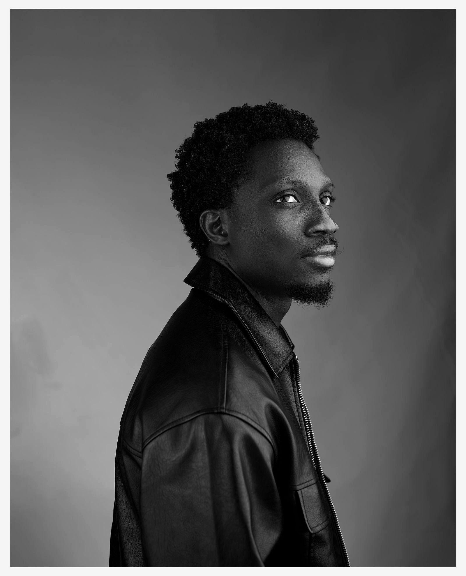 Greatman Takit in a leather jacket, photographed in profile.