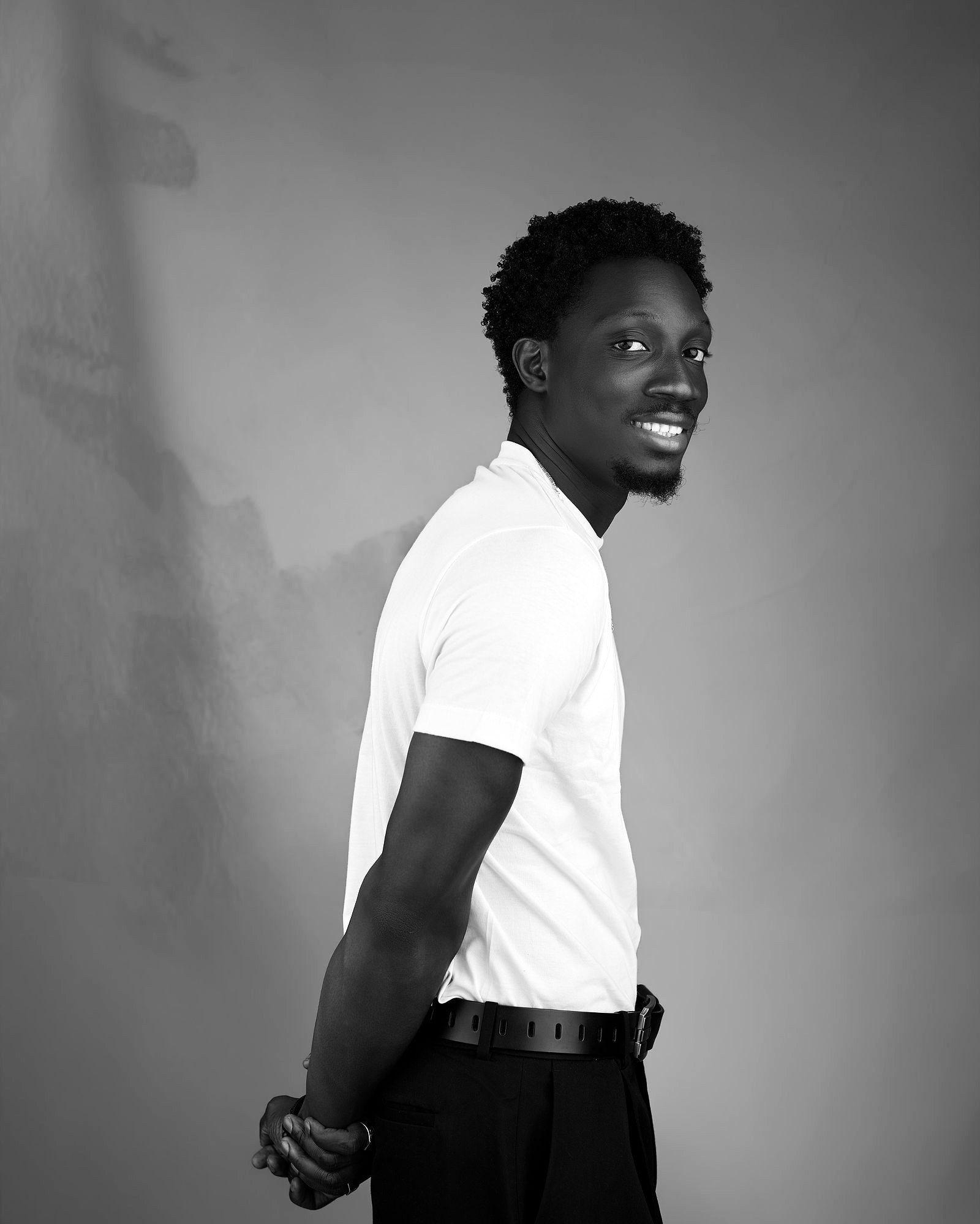 Side portrait of Greatman Takit turning towards the camera.